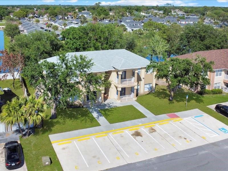 An aerial view shows a two-story apartment building with balconies and a paved parking lot — 206 MAJORS LANE UNIT A, KISSIMMEE, FL