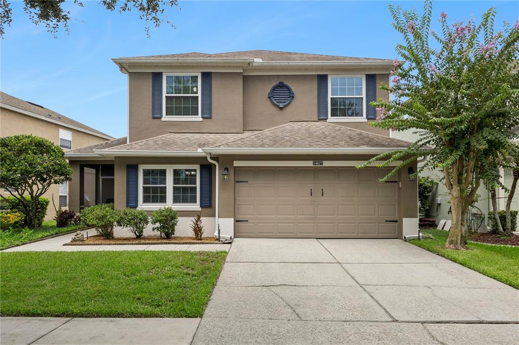 A two-story suburban house with a tan stucco exterior, a two-car garage, and blue shutters — 14827 MASTHEAD LANDING CIRCLE, WINTER GARDEN, FL