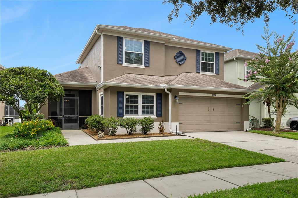 A two-story suburban house with a tan stucco exterior, blue shutters, and a two-car garage — 14827 MASTHEAD LANDING CIRCLE, WINTER GARDEN, FL