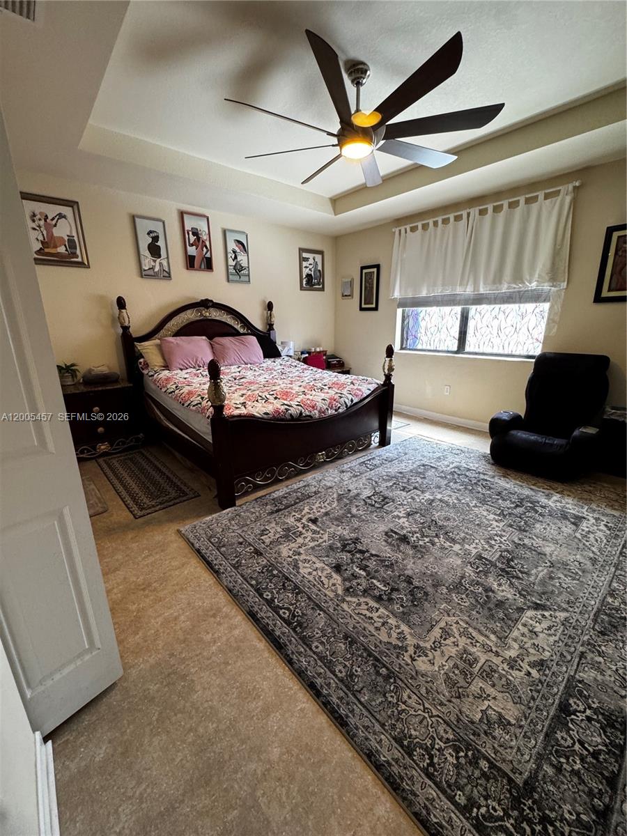 A bedroom features a dark wood bed frame, a large patterned rug, and a ceiling fan — 595 SE 33rd Ter, Homestead FL 33033, HOMESTEAD, FL