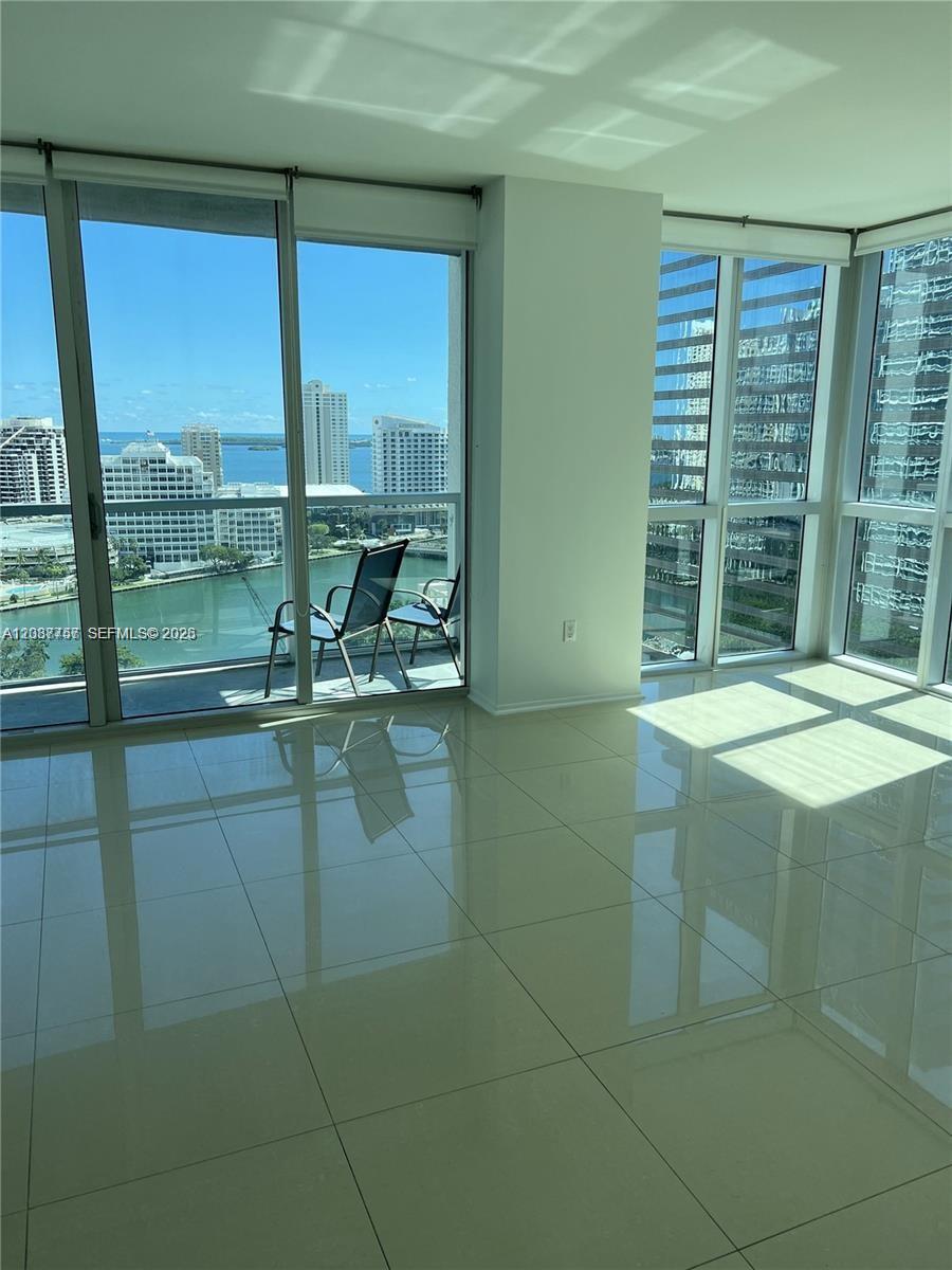 A bright room with light tile floors features floor-to-ceiling windows overlooking a city waterfront — 500 Brickell Ave # 2102, Miami FL 33131, MIAMI, FL