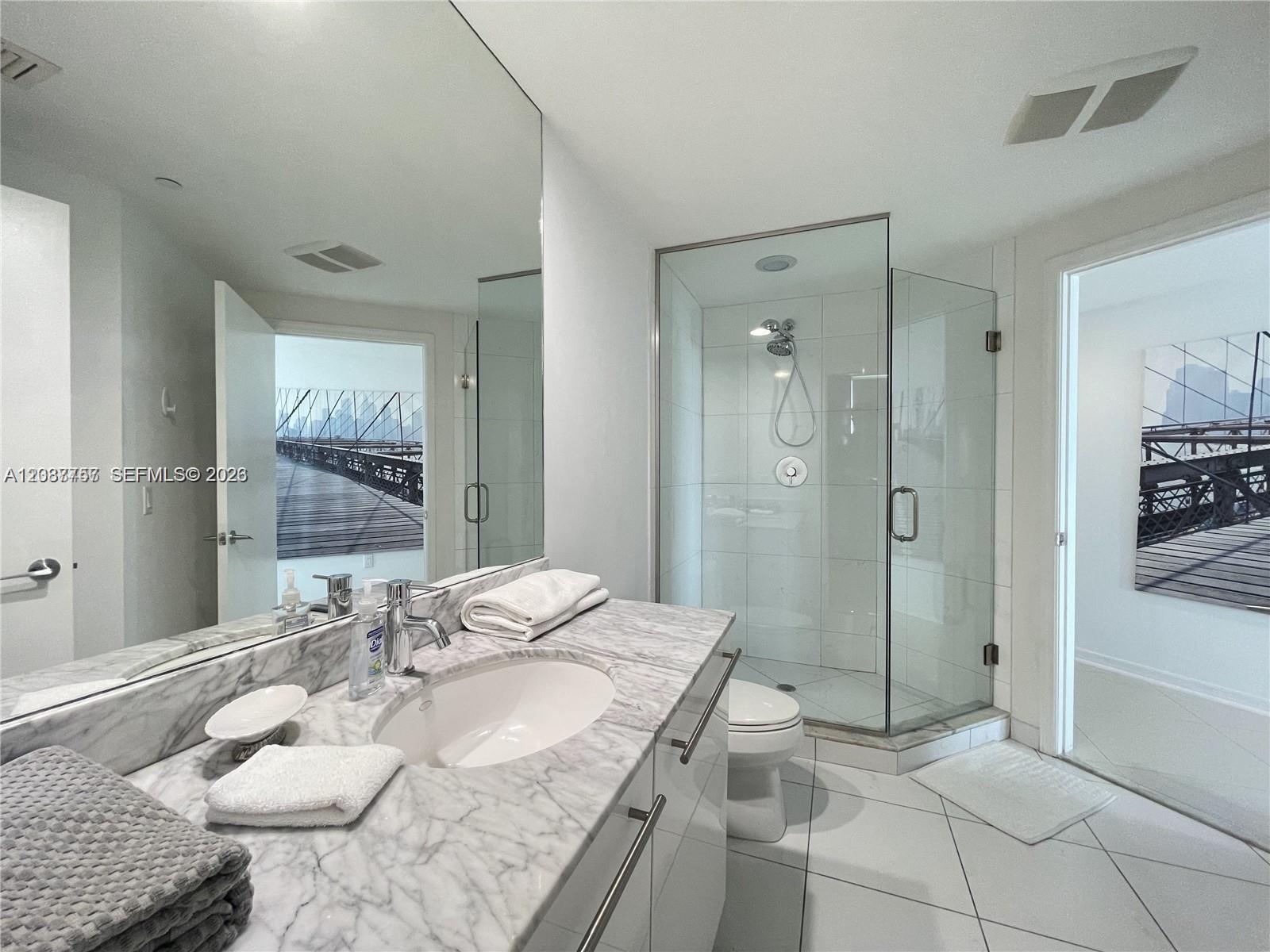 A modern bathroom features a marble vanity, a glass-enclosed shower, and white tile flooring — 500 Brickell Ave # 2102, Miami FL 33131, MIAMI, FL