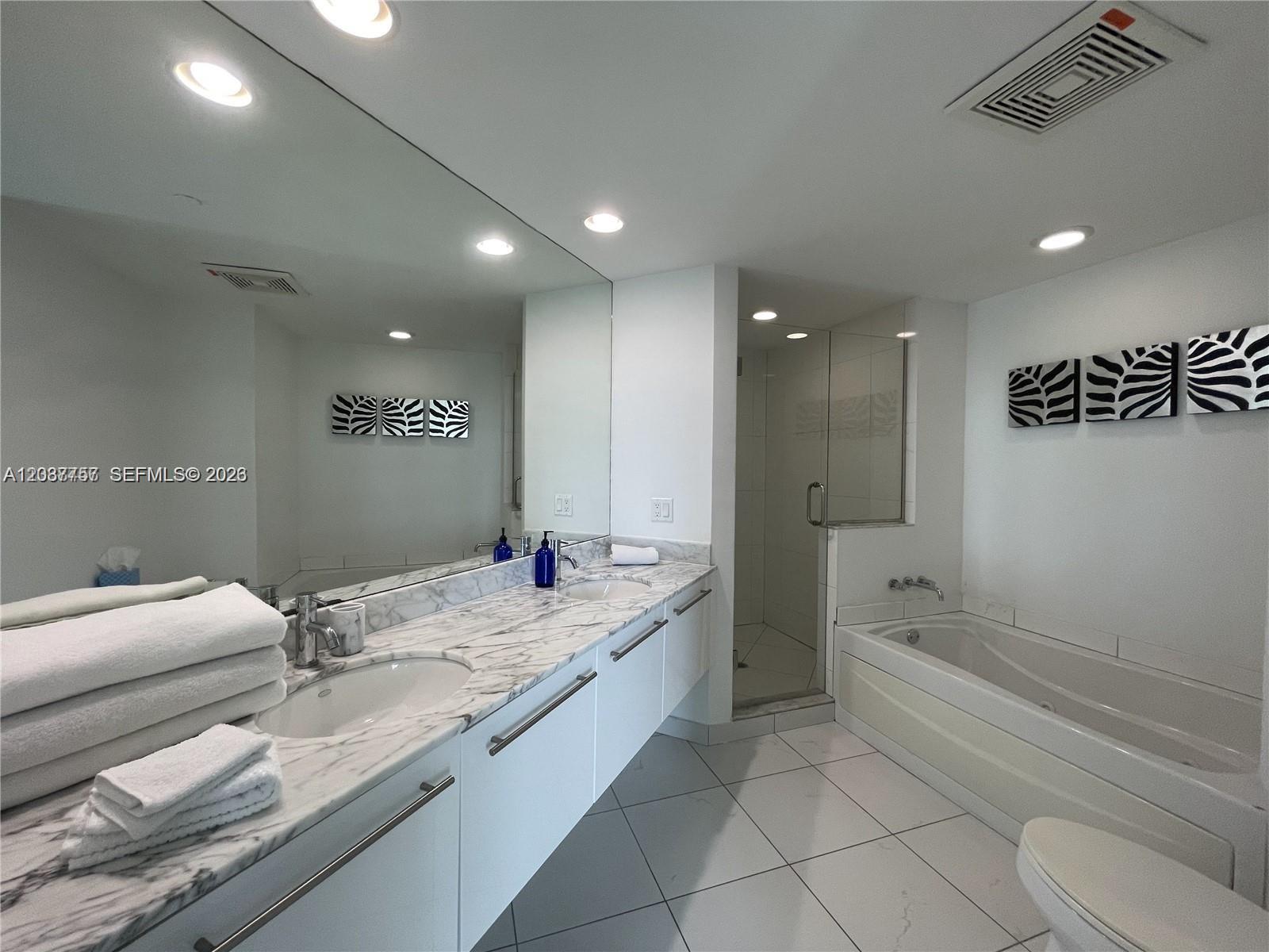 A modern bathroom features a double vanity with marble countertops, a glass shower, and a tub — 500 Brickell Ave # 2102, Miami FL 33131, MIAMI, FL
