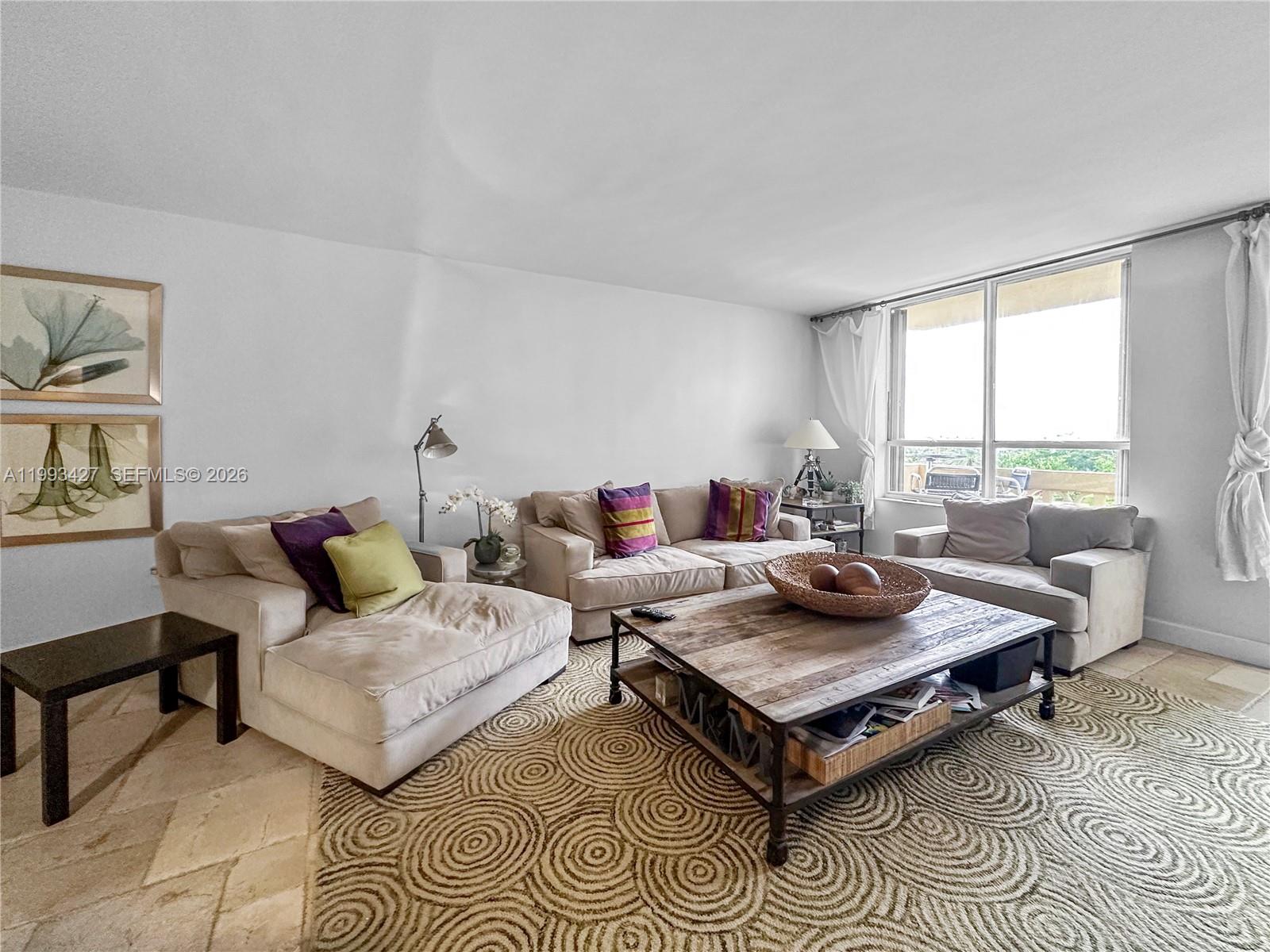 A living room features beige sofas, a wooden coffee table, and a patterned area rug — 10185 Collins Ave # 502, Bal Harbour FL 33154, BAL HARBOUR, FL