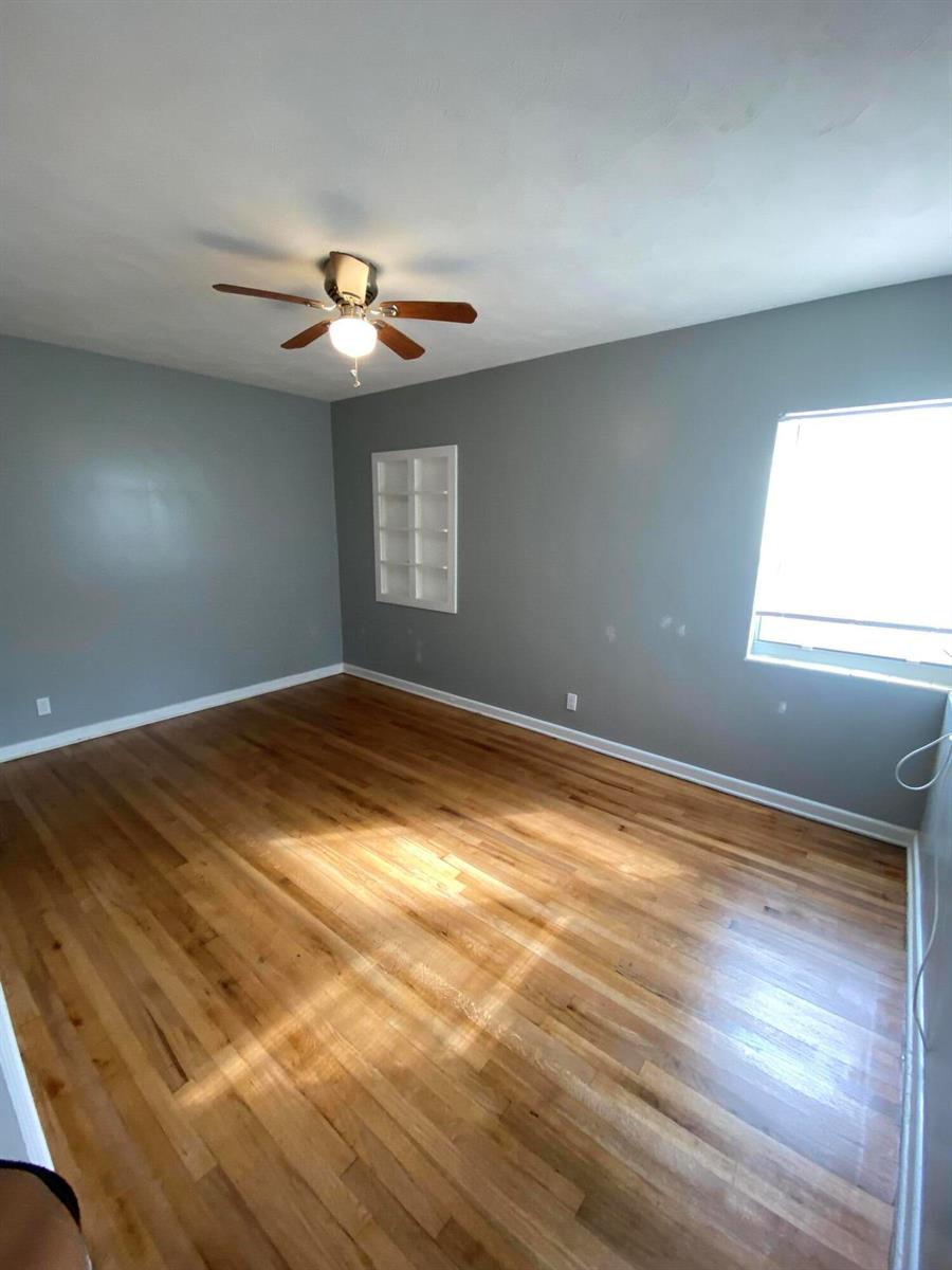 An empty room with gray walls, hardwood floors, a ceiling fan, and a built-in shelf — 119 W 25th Street # B, Riviera Beach FL 33404, RIVIERA BEACH, FL