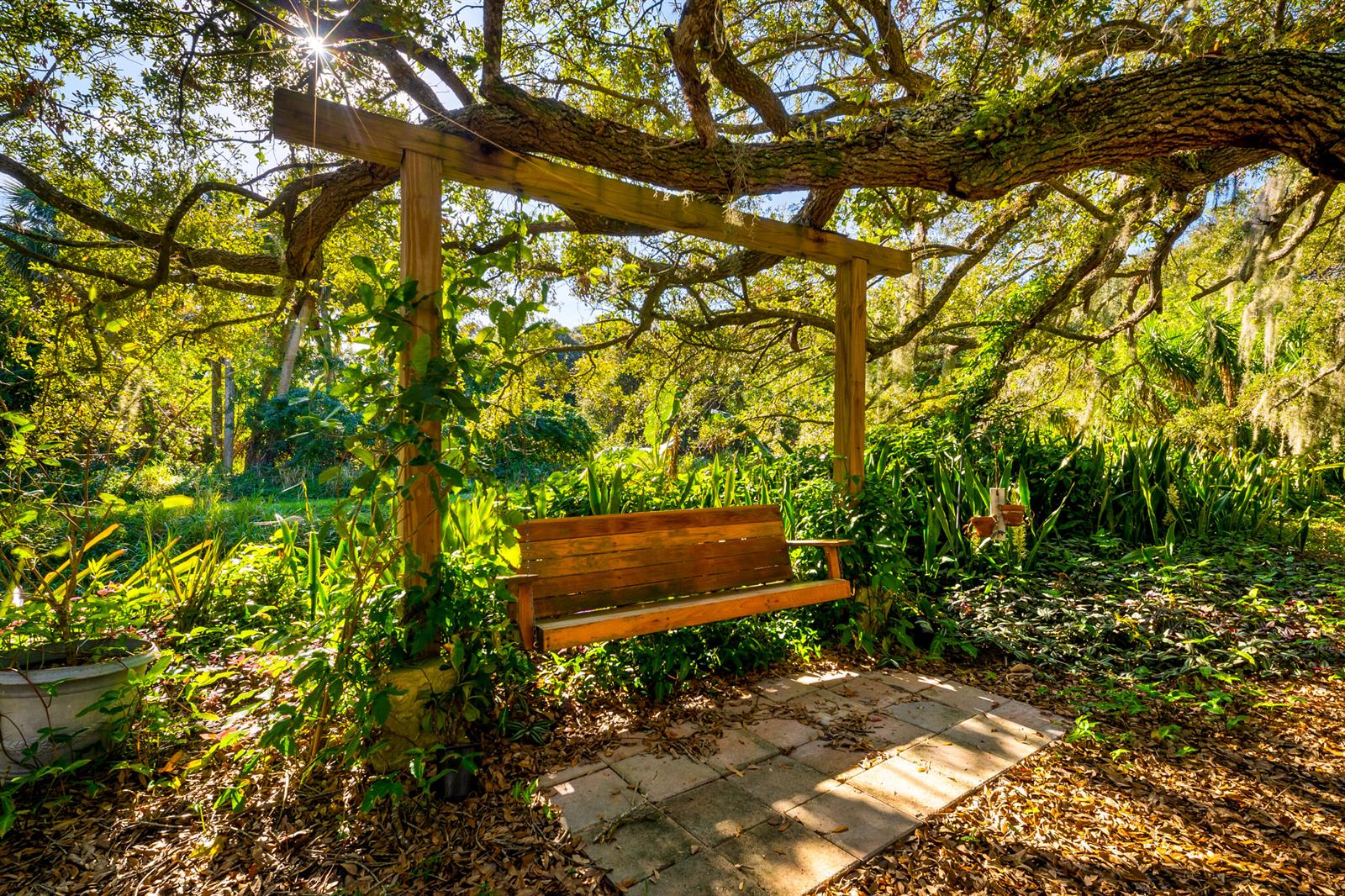 A wooden porch swing hangs from a pergola structure beneath a large, mossy oak tree — 2210 Saint Lucie Boulevard, Fort Pierce FL 34946, FORT PIERCE, FL