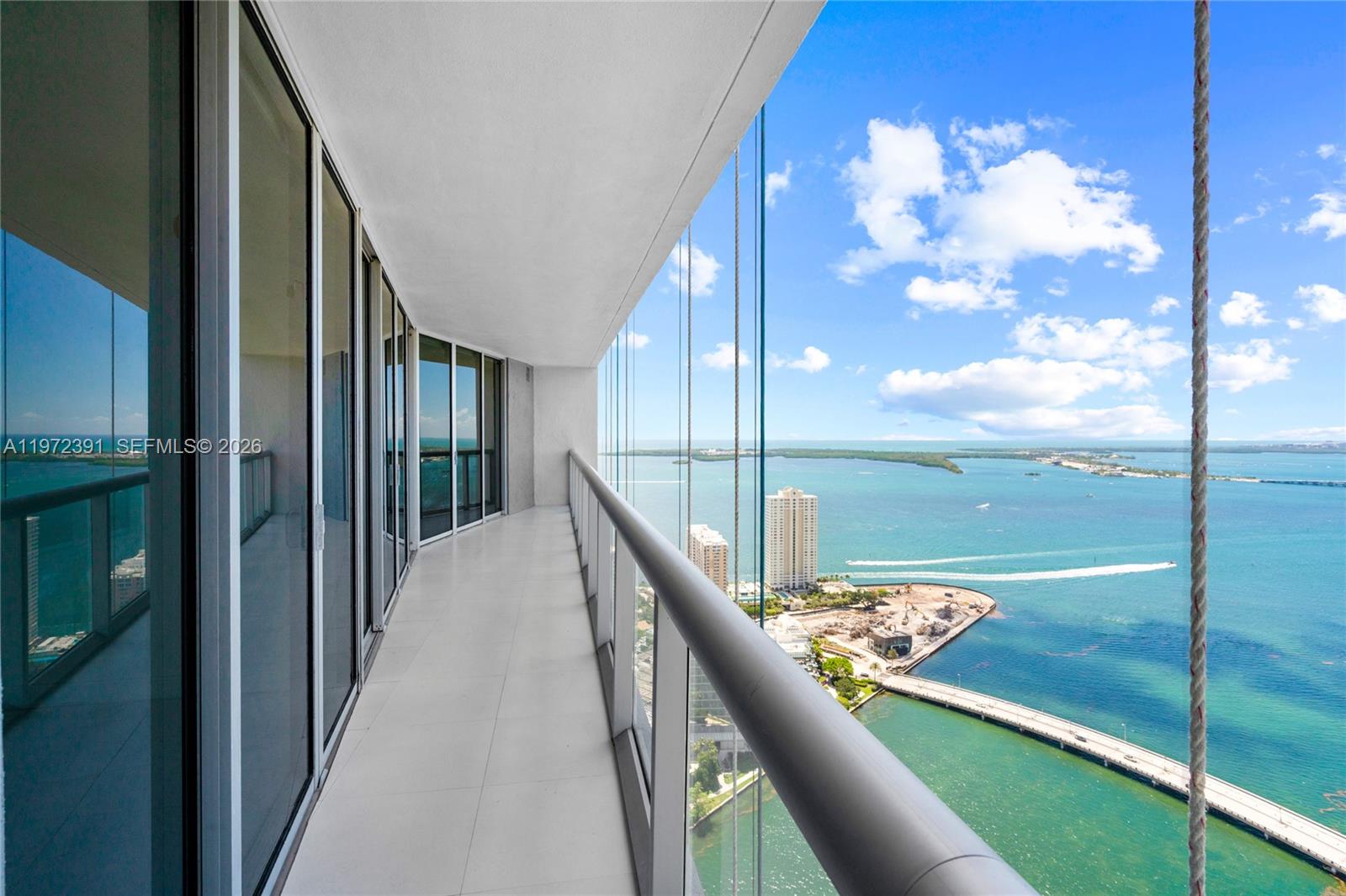A high-rise balcony with glass railings overlooks a bay, a bridge, and distant buildings — 495 Brickell Ave # 4705, Miami FL 33131, MIAMI, FL