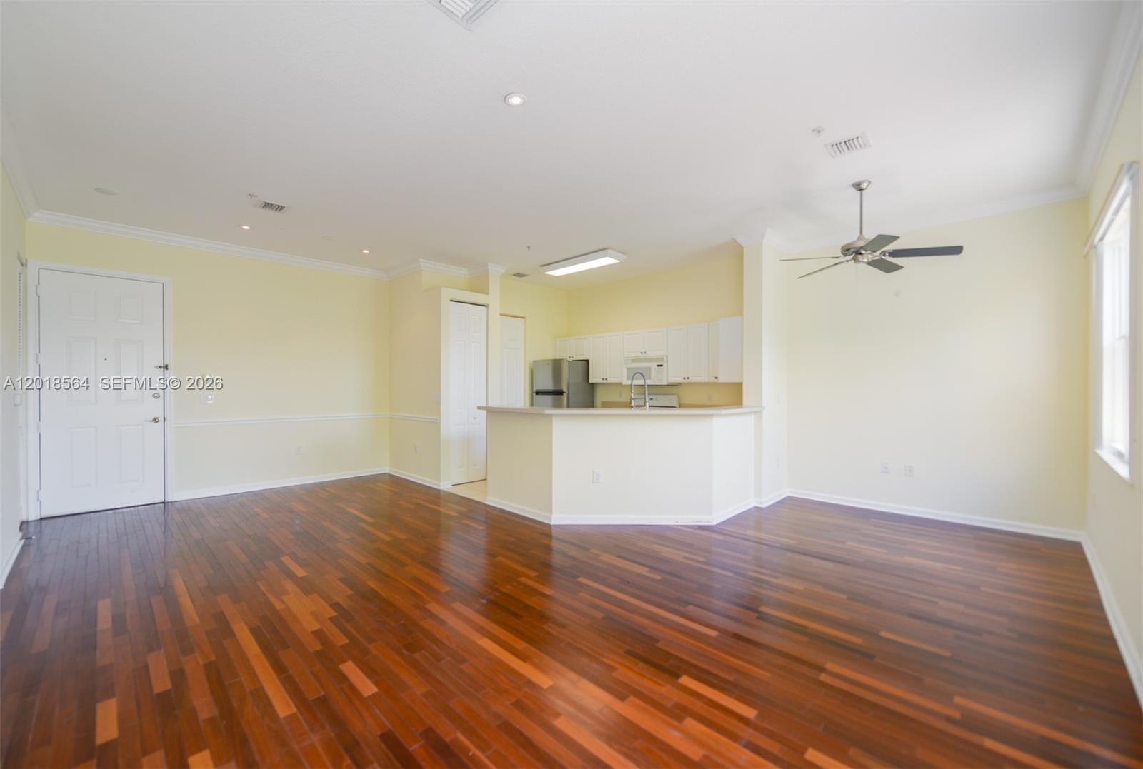 An open-concept living area features hardwood floors, a kitchen with white cabinets, and a ceiling fan — 4402 SW 160th Ave # 934, Miramar FL 33027, MIRAMAR, FL