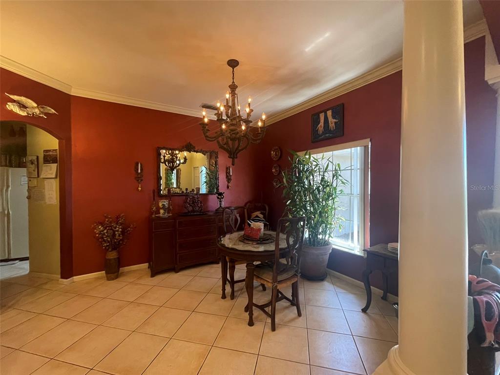 A dining room features red walls, tile flooring, a chandelier, and a round table — 5607 OAK GROVE COURT, SARASOTA, FL