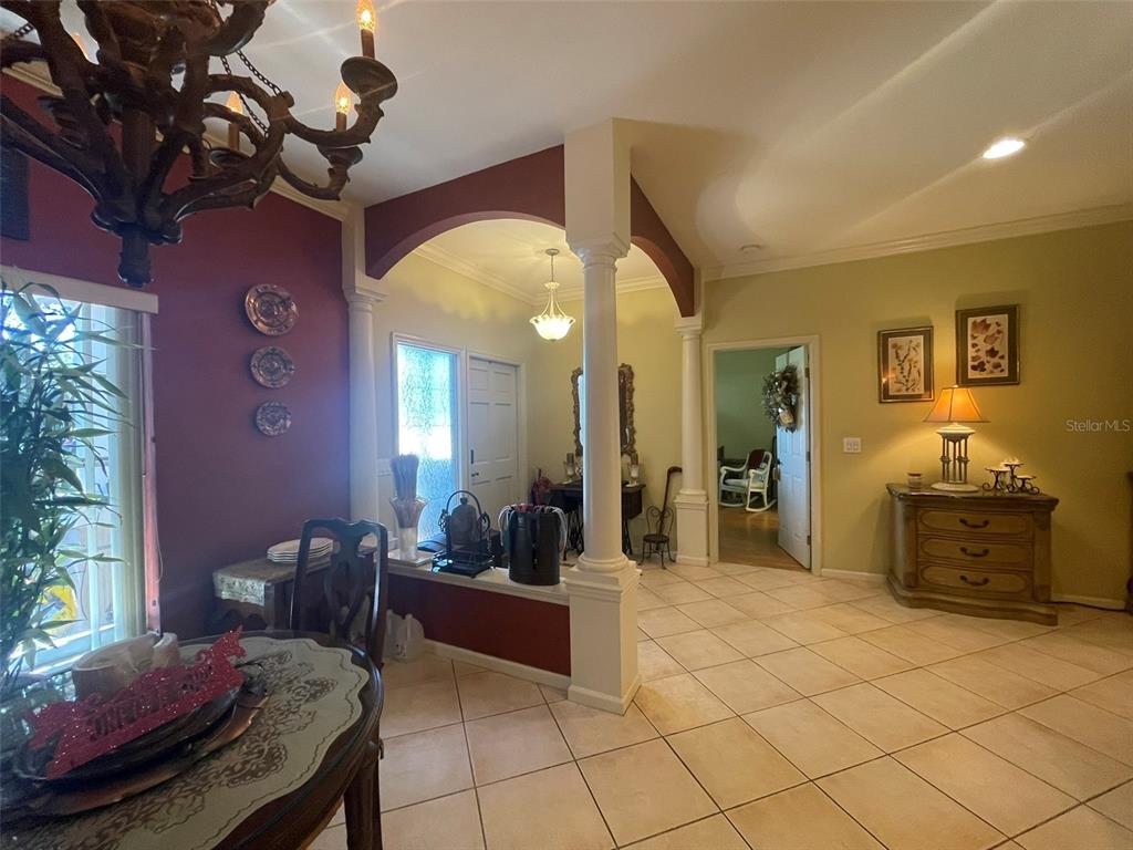 A dining area with a chandelier opens into a tiled foyer with arched architectural columns — 5607 OAK GROVE COURT, SARASOTA, FL