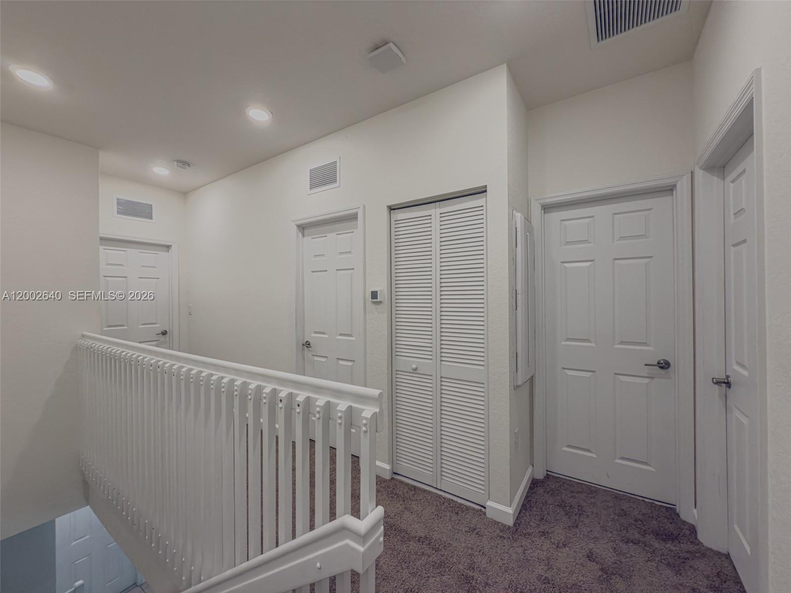 A carpeted hallway features a white railing, multiple interior doors, and a louvered closet — 10629 W 32nd Ln, Miami Lakes FL 33018, MIAMI LAKES, FL