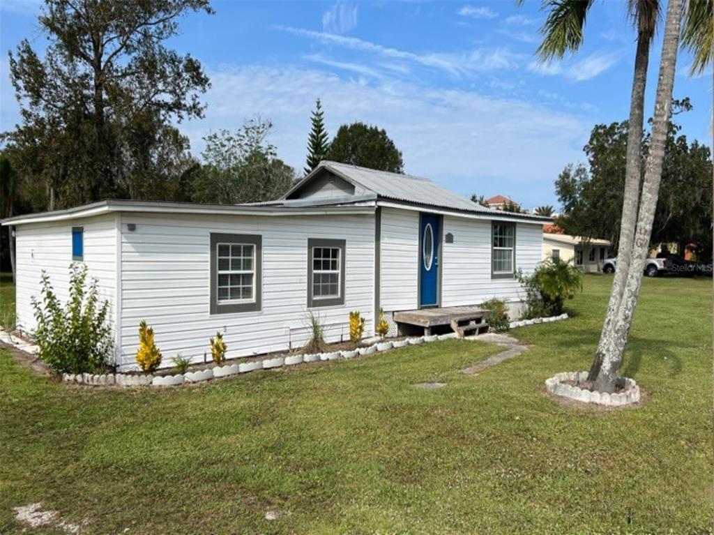 A white, single-story house with a metal roof and a blue front door — 34 S DEAN ROAD, ORLANDO, FL