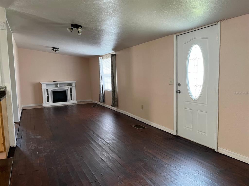 A living room features dark wood flooring, light pink walls, a white fireplace, and a door — 34 S DEAN ROAD, ORLANDO, FL