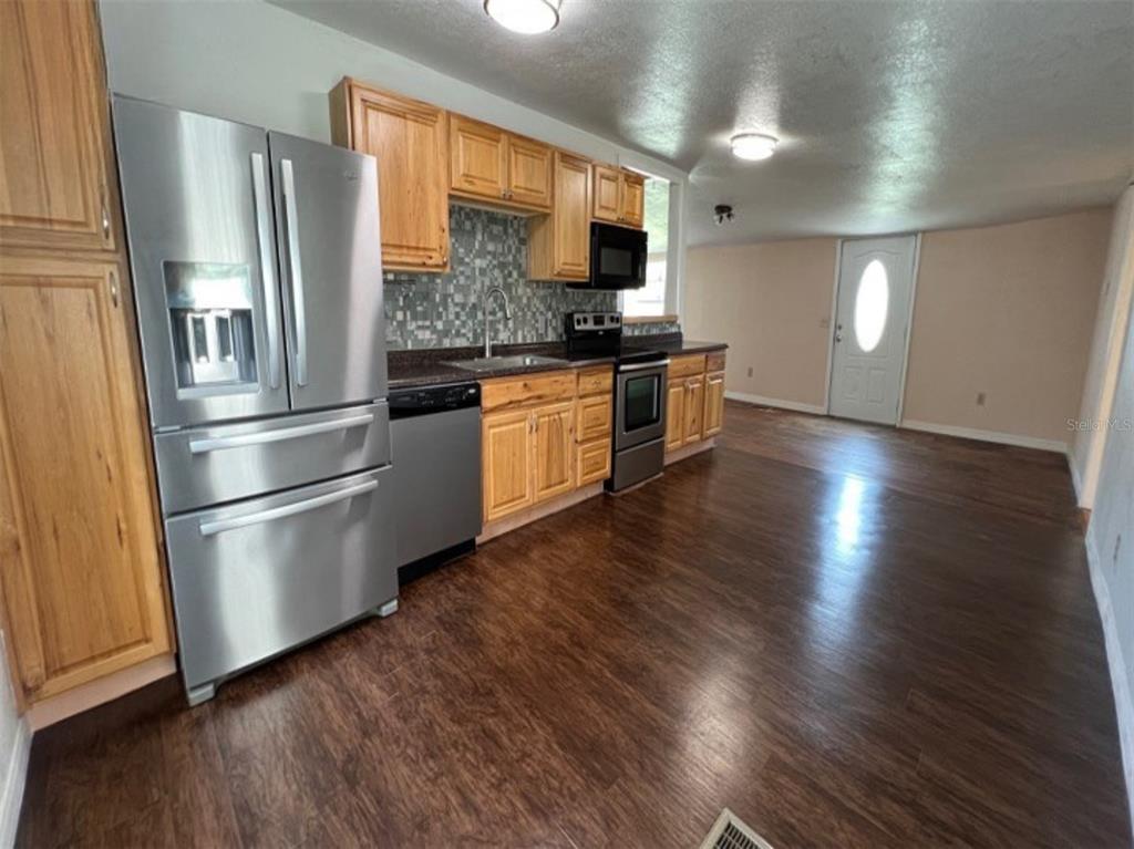 A kitchen with wood cabinets, stainless steel appliances, and dark wood flooring — 34 S DEAN ROAD, ORLANDO, FL