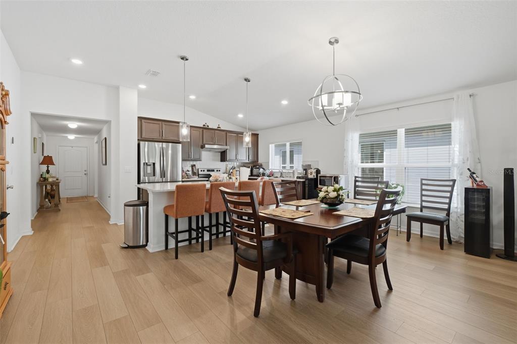 An open-concept kitchen and dining area features wood-look flooring, dark cabinetry, and a central island — 13085 THATCH PALM WAY, ORLANDO, FL