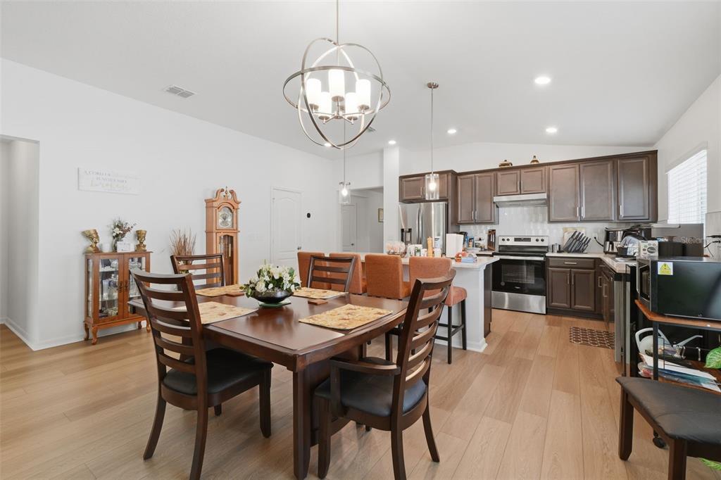 A dining area and kitchen with dark wood cabinets, stainless steel appliances, and wood flooring — 13085 THATCH PALM WAY, ORLANDO, FL