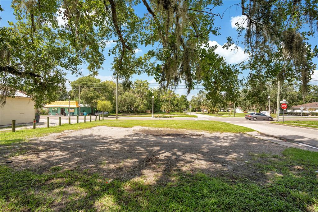 A vacant dirt lot is surrounded by grass, trees, and nearby street infrastructure — 1401 HISTORIC GOLDSBORO BOULEVARD, SANFORD, FL
