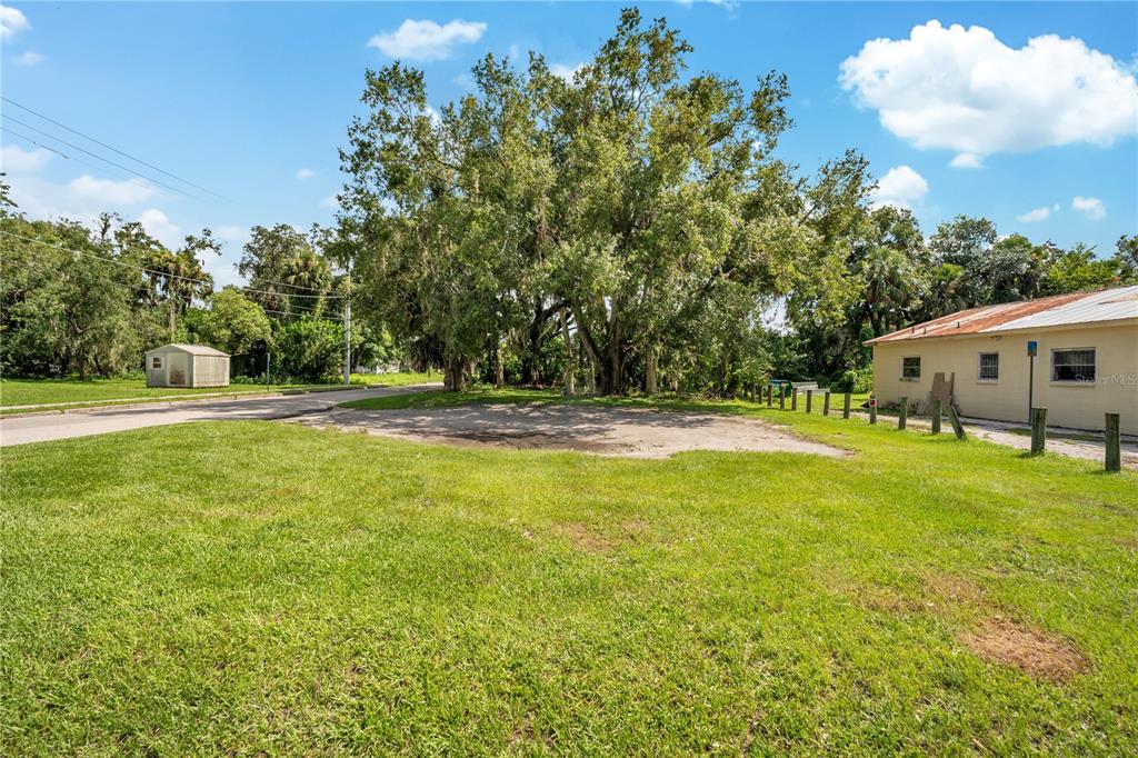 A grassy lot features a large tree, a small shed, and a side of a building — 1401 HISTORIC GOLDSBORO BOULEVARD, SANFORD, FL