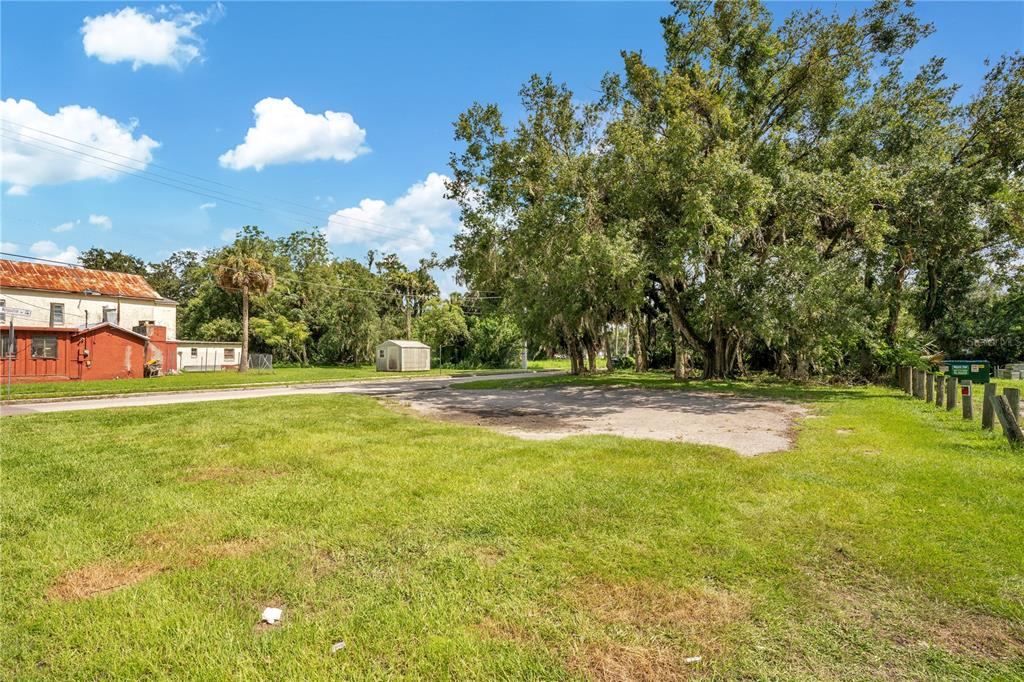 A grassy vacant lot features a large tree and a small shed near a road — 1401 HISTORIC GOLDSBORO BOULEVARD, SANFORD, FL