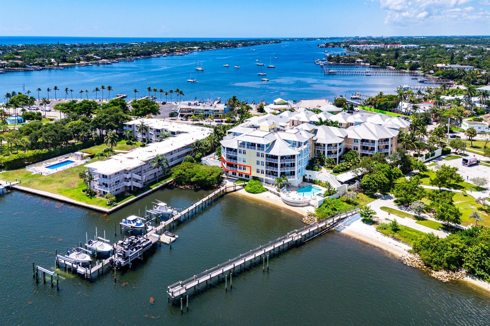 An aerial view shows a multi-story waterfront condominium building with a boat dock and pool — 309 E Ocean Avenue # 103, Lantana FL 33462, LANTANA, FL