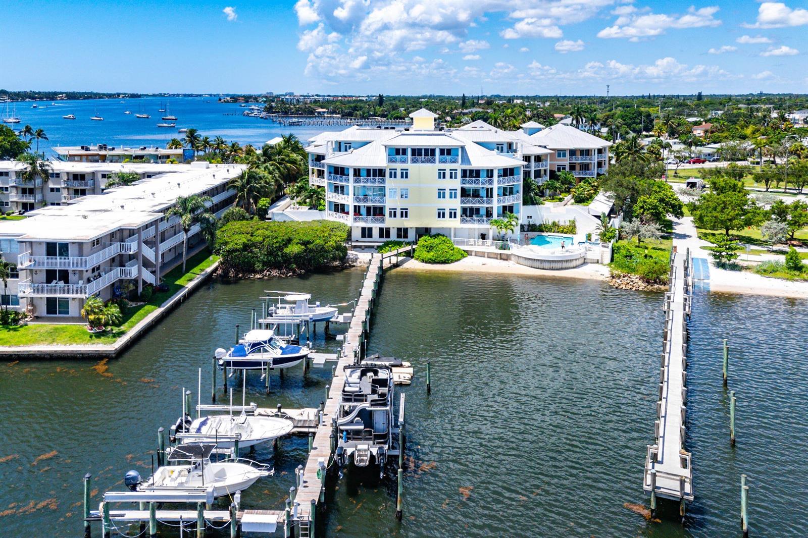 A covered balcony features white geometric railings, a ceiling fan, and views of a boat dock — 309 E Ocean Avenue # 103, Lantana FL 33462, LANTANA, FL