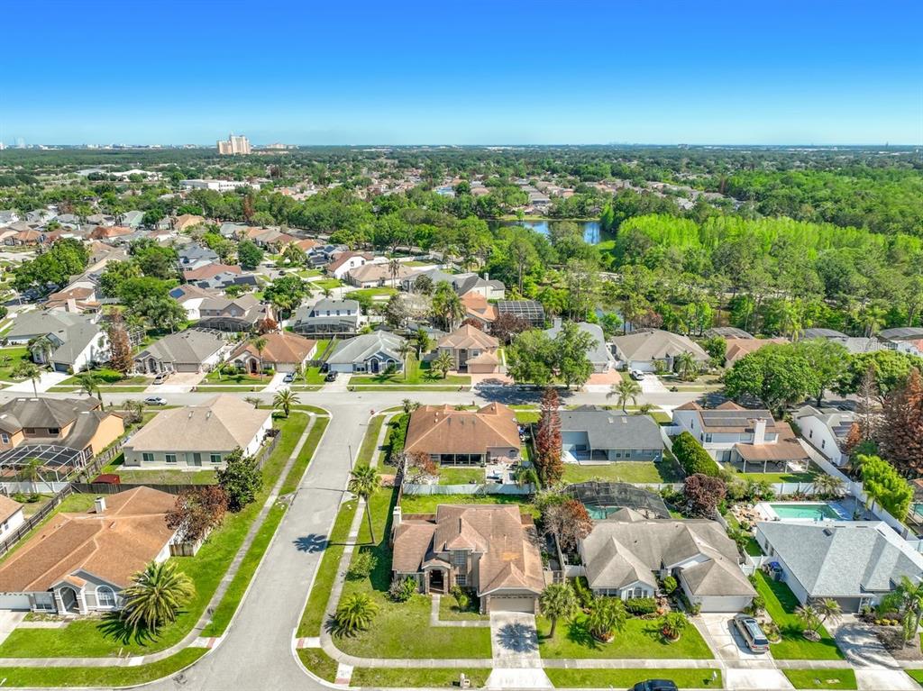 An aerial view shows a suburban neighborhood with single-family homes, green lawns, and a lake — 2645 ROLLING BROAK DRIVE, ORLANDO, FL
