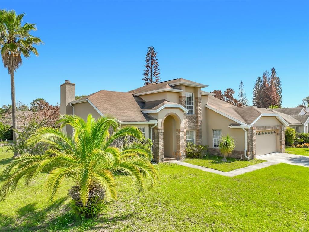 A two-story suburban house with a tan stucco exterior, brick accents, and a front lawn — 2645 ROLLING BROAK DRIVE, ORLANDO, FL