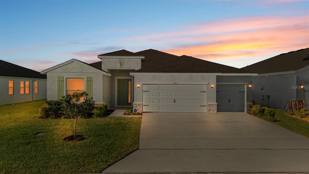 A single-story suburban house with a two-car garage and a green front door — 3507 GOLDEN WHEAT LANE, PLANT CITY, FL