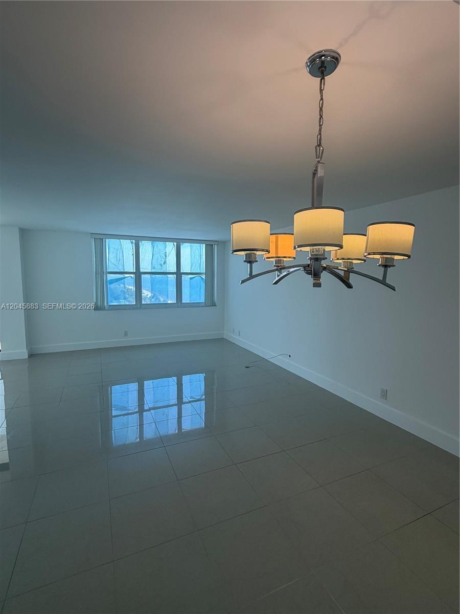 An empty room features large light-colored floor tiles, white walls, and a modern chandelier — 2201 S Ocean Dr # 1905, Hollywood FL 33019, HOLLYWOOD, FL