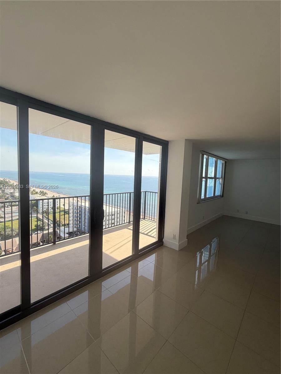 An empty room with beige tile floors features a balcony overlooking the ocean — 2201 S Ocean Dr # 1905, Hollywood FL 33019, HOLLYWOOD, FL