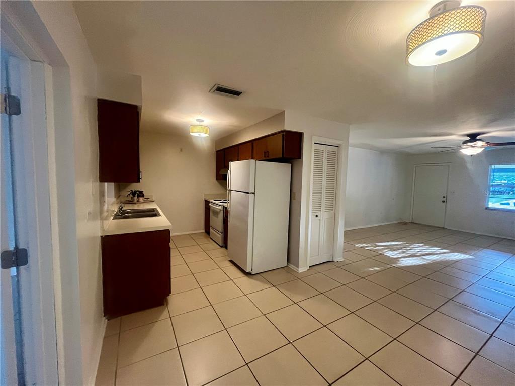 A kitchen with dark wood cabinets and white appliances opens into a tiled living area — 705 BAYOU AVENUE, TARPON SPRINGS, FL