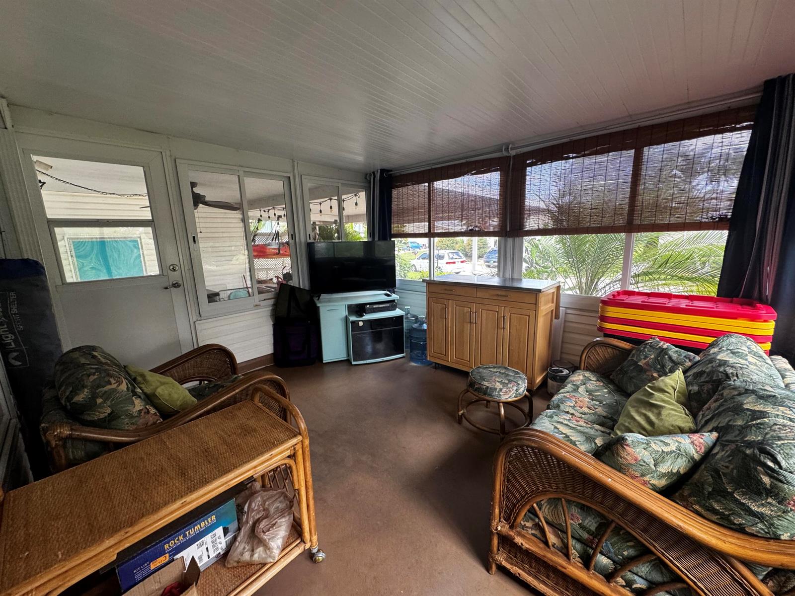 A sunroom features wicker furniture, a television on a stand, and large windows with shades — 4081 4th Court, Lantana FL 33462, LANTANA, FL