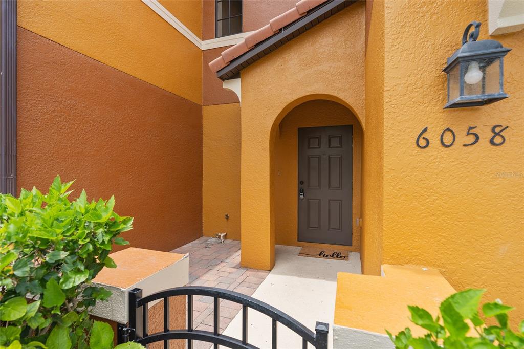 The exterior of a home features a yellow stucco facade, a dark door, and a lantern — 6058 TIVOLI GARDENS BOULEVARD, ORLANDO, FL