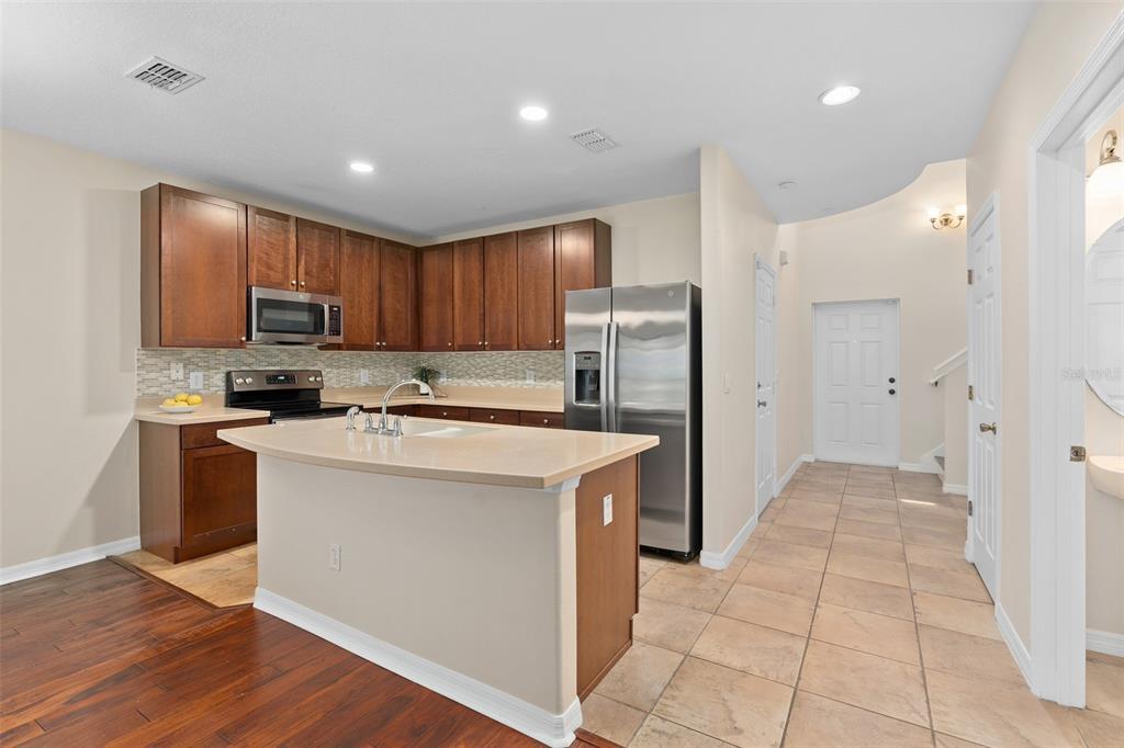 A kitchen with dark wood cabinets, stainless steel appliances, a center island, and tile flooring — 6058 TIVOLI GARDENS BOULEVARD, ORLANDO, FL