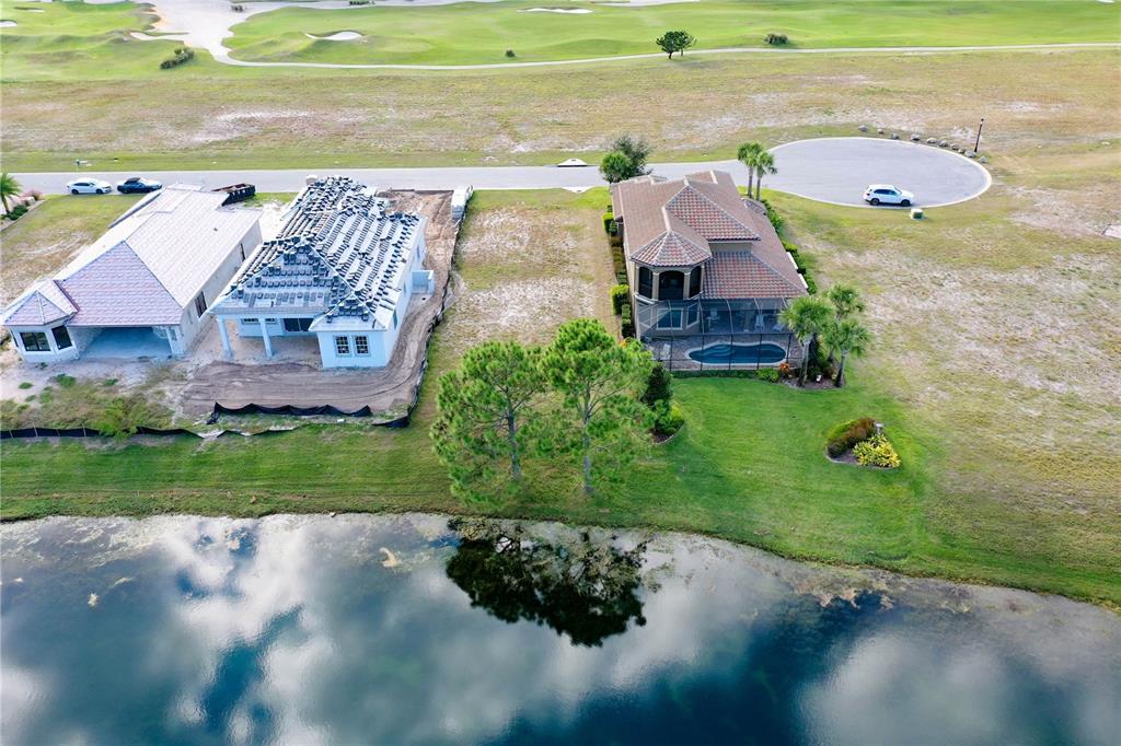 An aerial view shows two houses near a pond, one under construction and one finished — 355 HIBISCUS WAY, PALM COAST, FL
