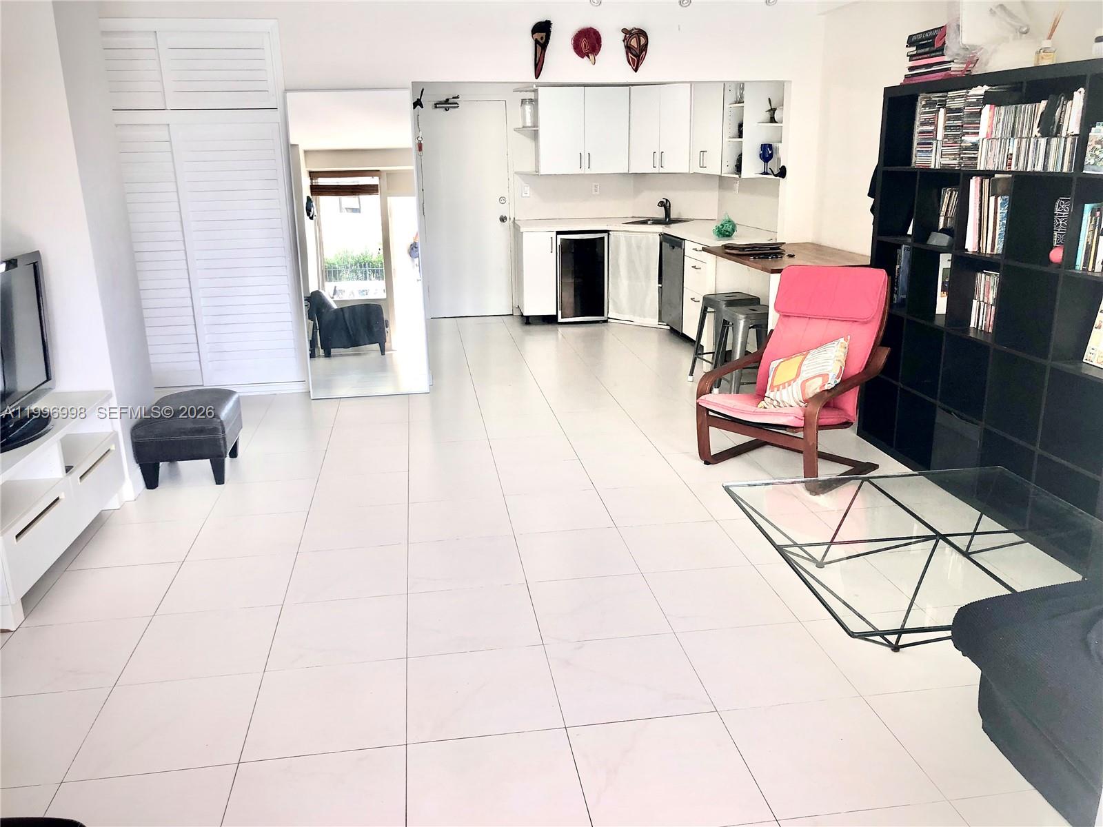 A studio apartment features white tile floors, a small kitchenette, and a pink armchair — 1430 Brickell Bay Dr. # 106, Miami FL 33131, MIAMI, FL