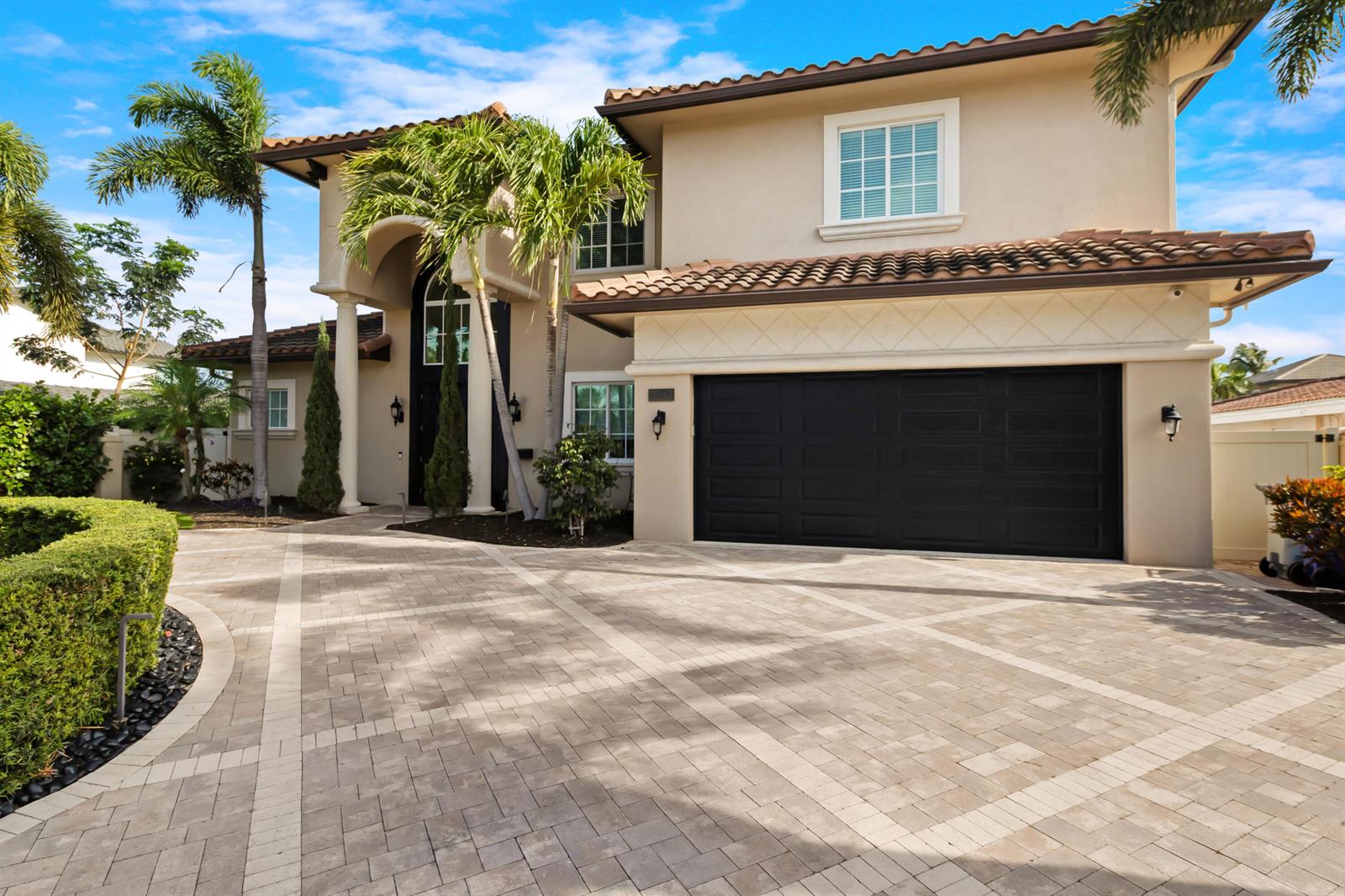 A two-story house with a beige stucco exterior, a black garage door, and a paver driveway — 2461 SE 10th Street, Pompano Beach FL 33062, POMPANO BEACH, FL