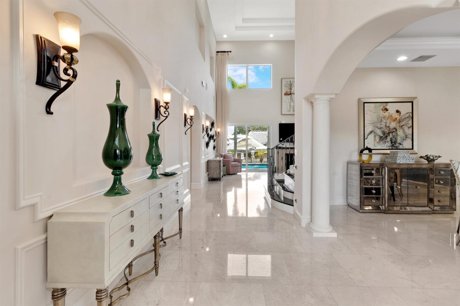 A bright, high-ceilinged foyer features marble floors, arched wall niches, and a mirrored console table — 2461 SE 10th Street, Pompano Beach FL 33062, POMPANO BEACH, FL