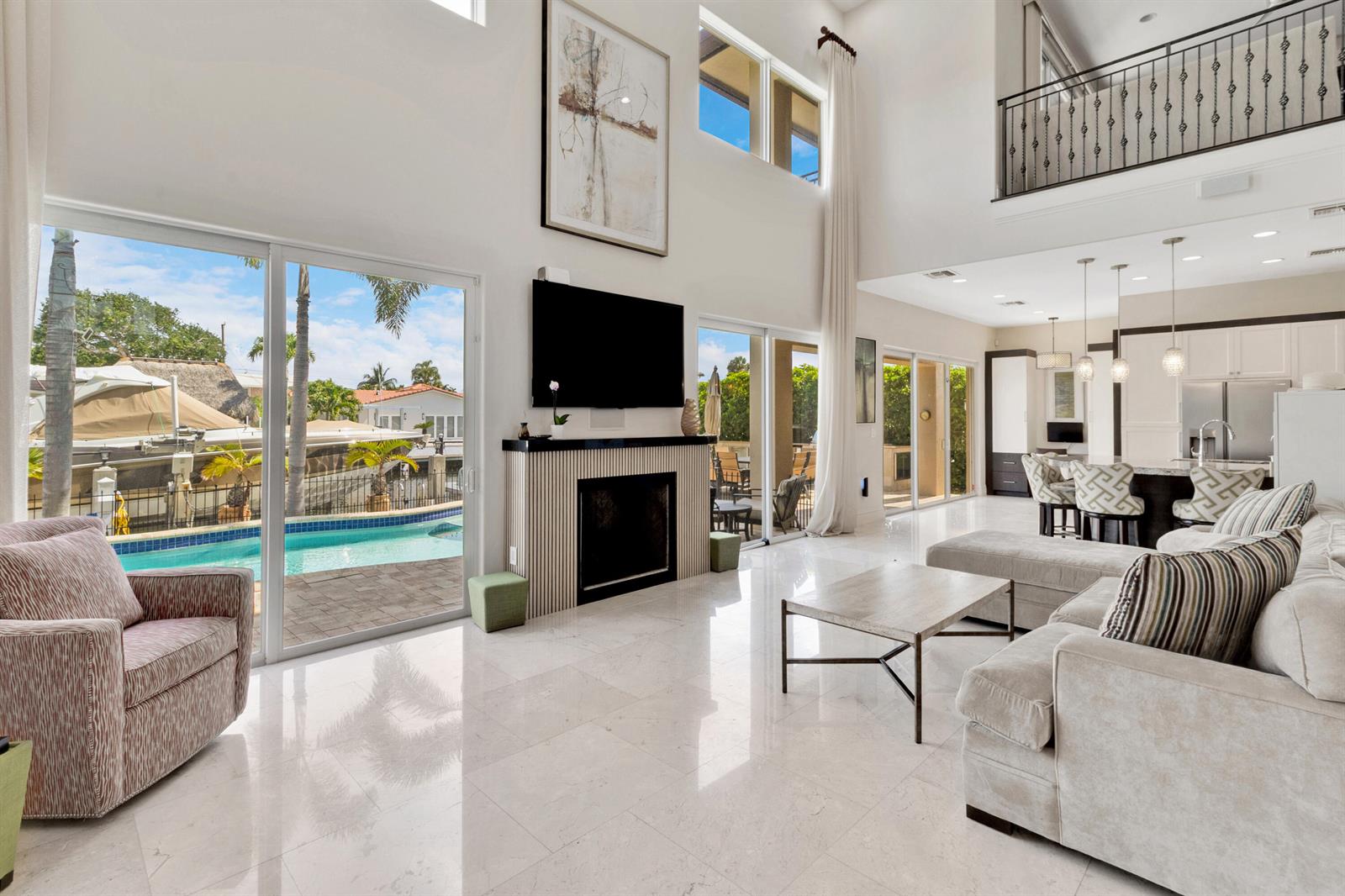 A bright living room features a fireplace, high ceilings, tile floors, and sliding glass doors — 2461 SE 10th Street, Pompano Beach FL 33062, POMPANO BEACH, FL