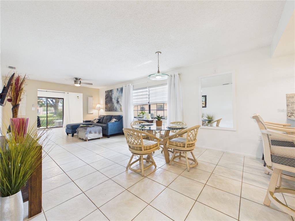 An open-concept living and dining area features tile flooring, a glass-topped table, and a sofa — 13250 RIDGE ROAD UNIT 9-8, LARGO, FL