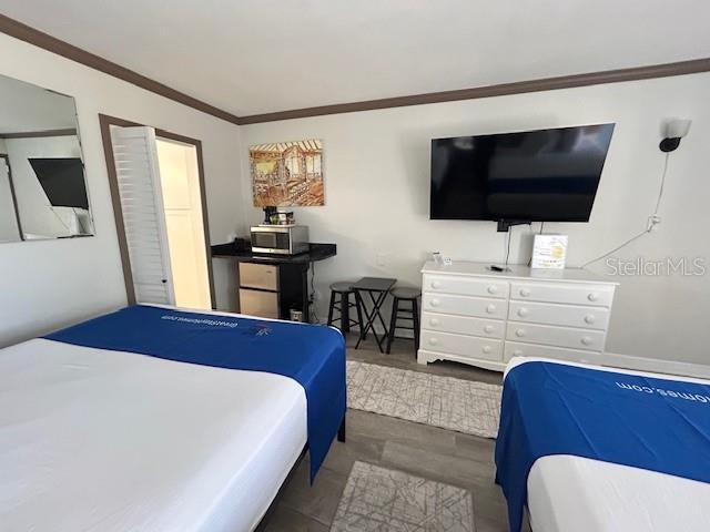 A bedroom features two beds, a television mounted above a white dresser, and a kitchenette — 7150 N TAMIAMI TRAIL UNIT C233, SARASOTA, FL
