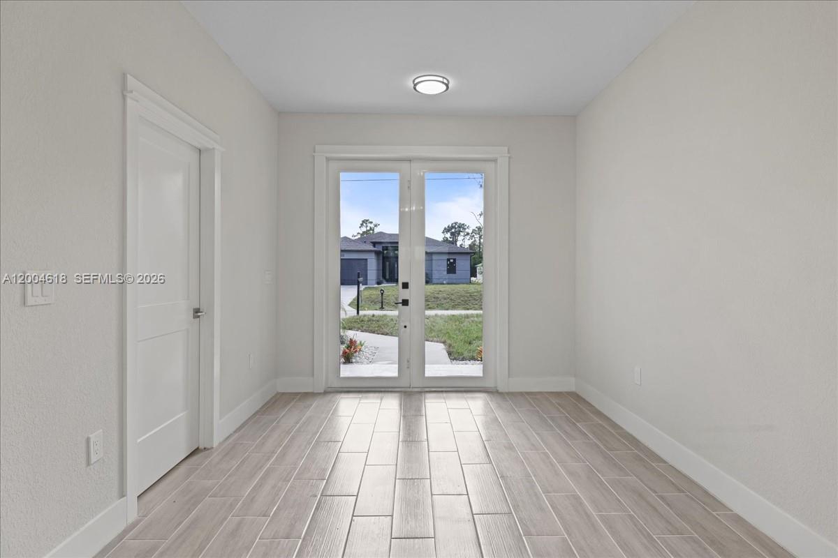 A bright entryway features light wood-look tile flooring, a white door, and double glass doors — 2804 11th ST W, Lehigh Acres FL 33971, LEHIGH ACRES, FL