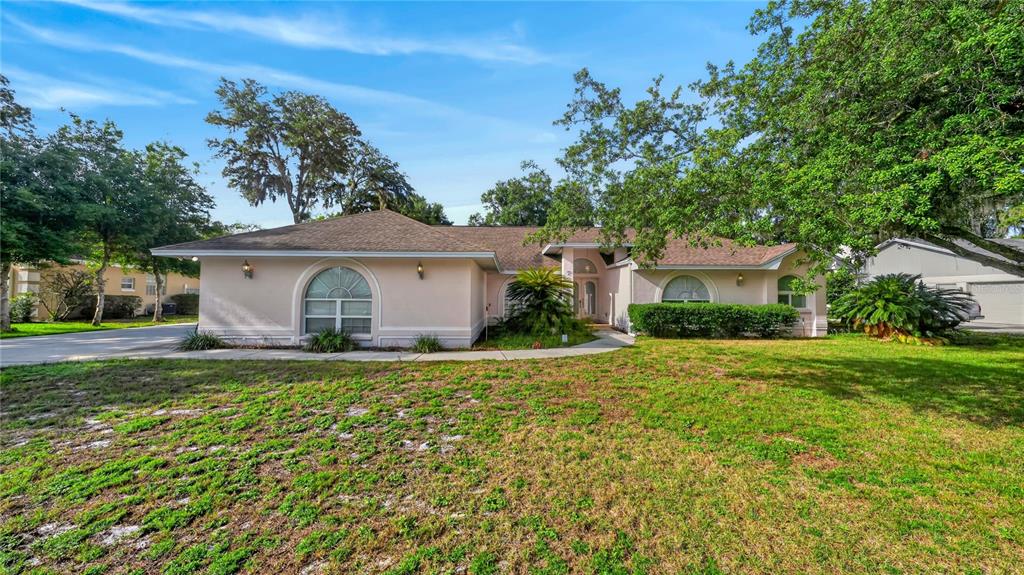 A single-story, light-colored house with a hip roof and arched windows sits on a lawn — 7222 STANFORD DR, LAKELAND, FL