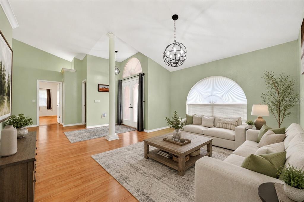 A living room with light green walls, hardwood floors, a vaulted ceiling, and arched windows — 7222 STANFORD DR, LAKELAND, FL