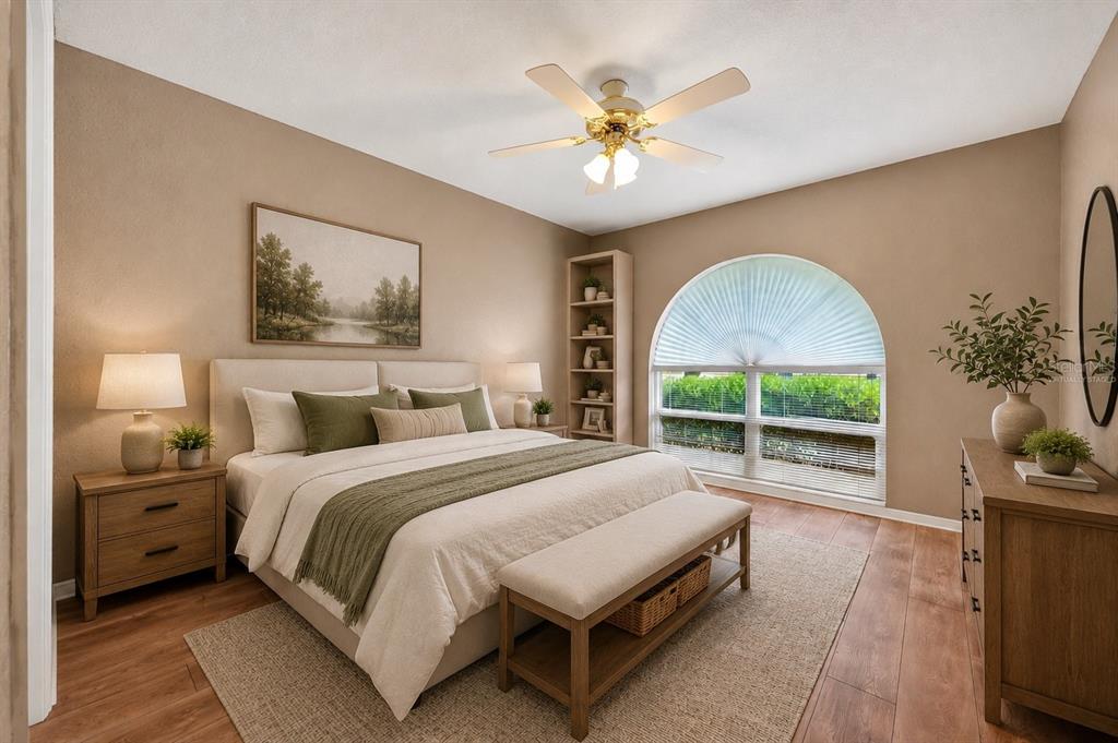 A bedroom with a bed, bench, nightstands, bookshelf, and an arched window with blinds — 7222 STANFORD DR, LAKELAND, FL