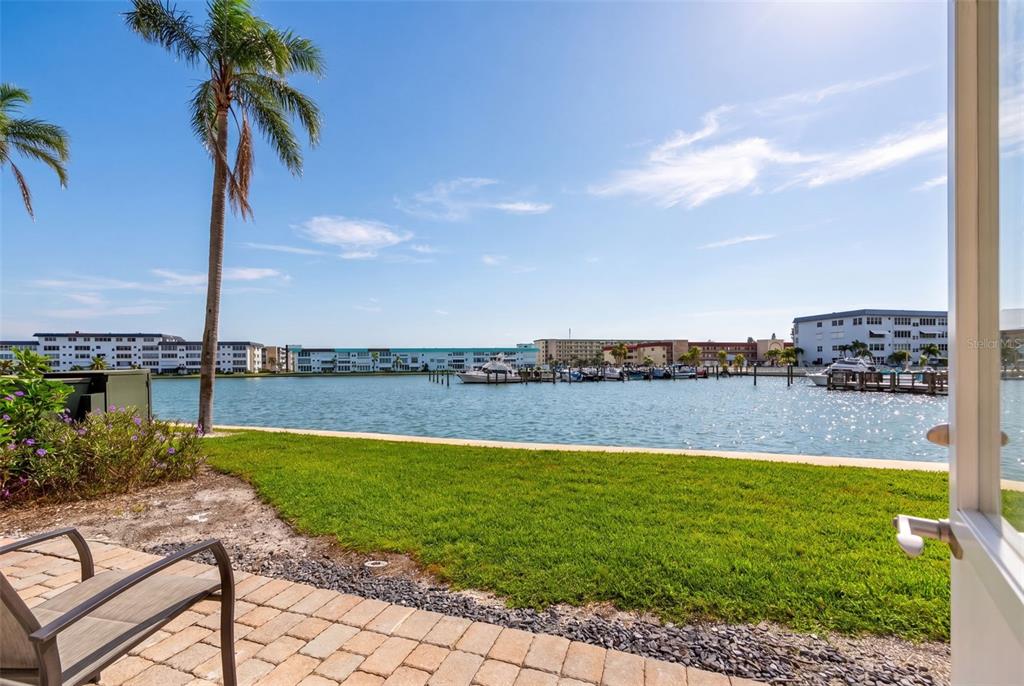 A view of a waterfront marina from a paved patio with a palm tree — 5925 SHORE BOULEVARD S UNIT 108, GULFPORT, FL