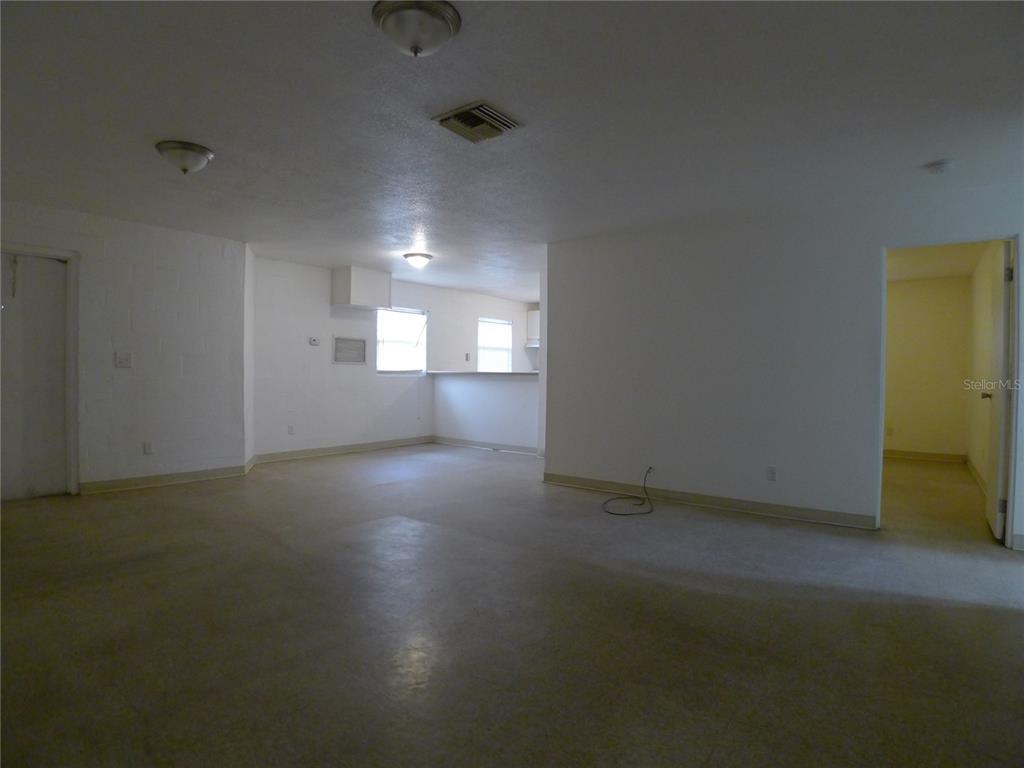 An open-concept living area features white walls, light-colored flooring, and a pass-through kitchen window — 3420 N 55TH STREET UNIT B, TAMPA, FL