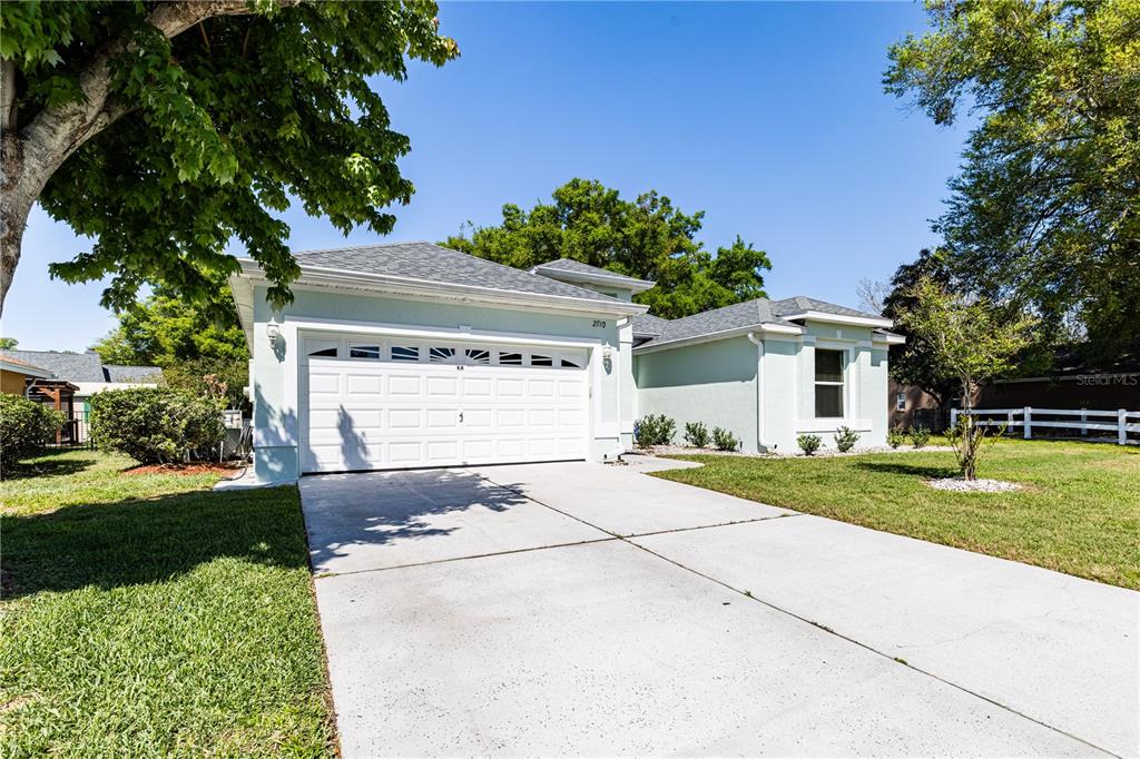 A light green single-story house with a two-car garage and a concrete driveway — 2710 AUTUMN LANE, EUSTIS, FL