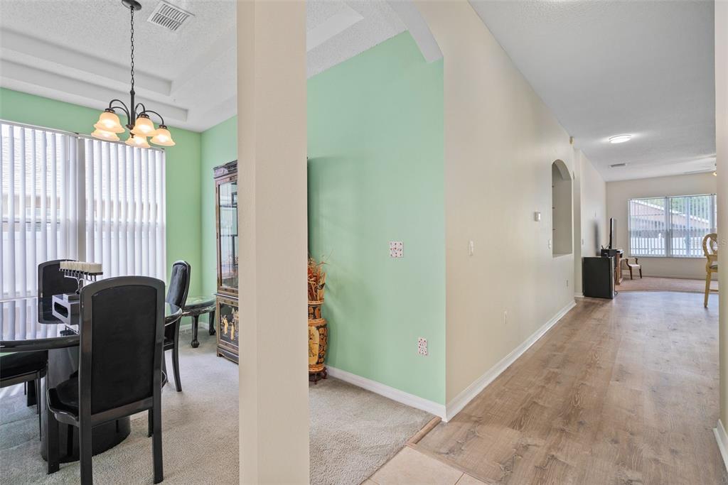 A dining room with a light green wall and carpeted floor sits beside a hallway — 726 SENECA MEADOWS ROAD, WINTER SPRINGS, FL