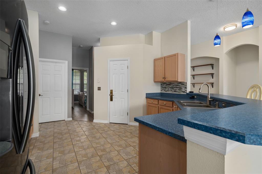 A kitchen with blue countertops, wood cabinets, tile flooring, and a view into a hallway — 726 SENECA MEADOWS ROAD, WINTER SPRINGS, FL